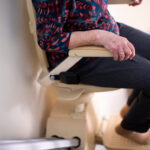 Elderly woman sitting in stair lift going down stairs